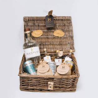 Gin lovers hamper with 70cl bottle, mini bottle, mixers, and garnish in a wicker basket.