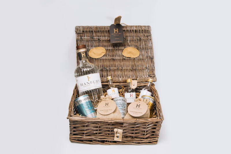 Gin lovers hamper with 70cl bottle, mini bottle, mixers, and garnish in a wicker basket.