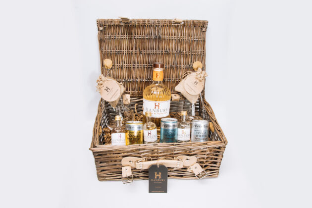 Ultimate gin hamper featuring 70cl bottle, mini bottles, mixers, garnishes, and branded glasses in a wicker basket