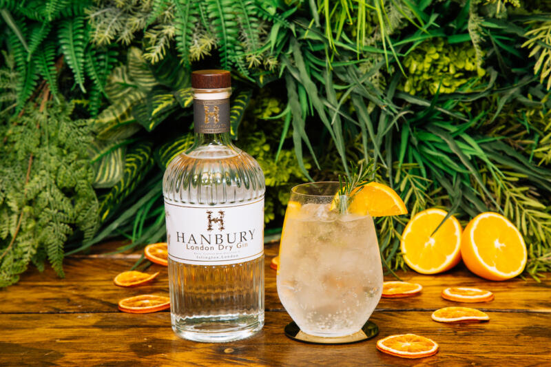 Hanbury London Dry Gin bottle with a gin and tonic in a glass.