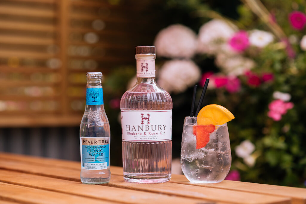 Hanbury Rhubarb & Rose Gin amidst a summer garden scene.