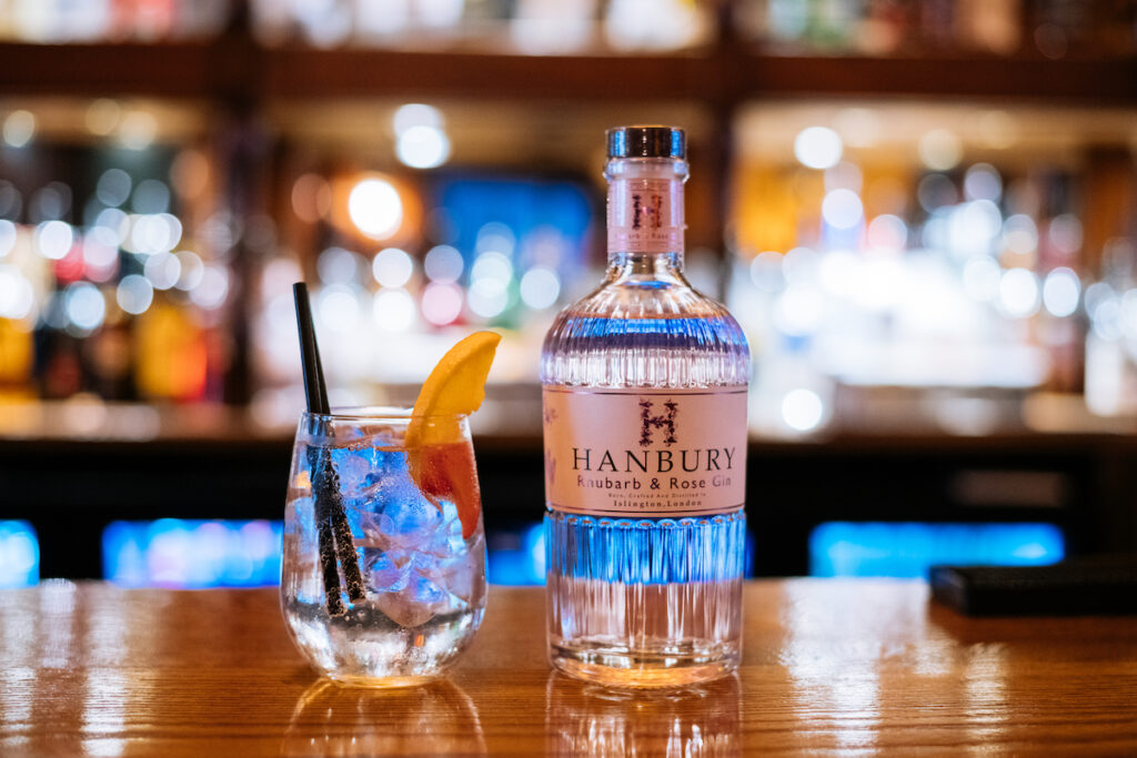 Hanbury Rhubarb and Rose Gin served with tonic on a bar counter.