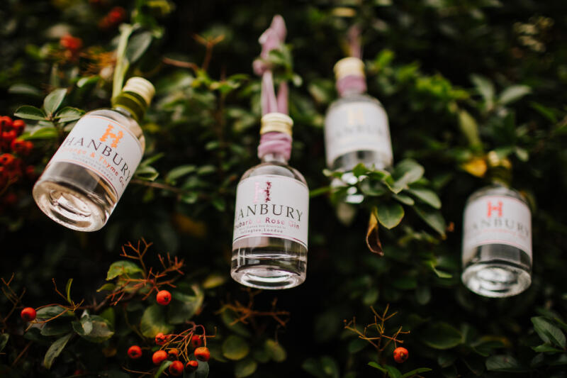 Miniature Hanbury gin collection hanging from a tree adorned with ribbon.